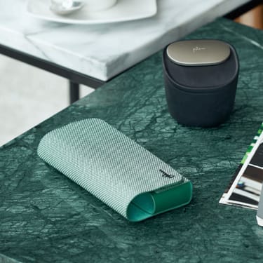 Zelené textilné puzdro na Ploom X Advanced a dóza na náplne na stole