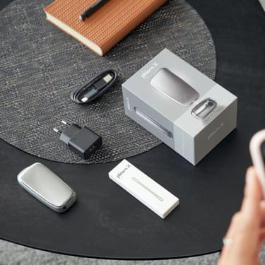 Obsah balenia Ploom X Advanced na stole - zariadenie, čistiace tyčinky, usb kábel, sieťový adaptér