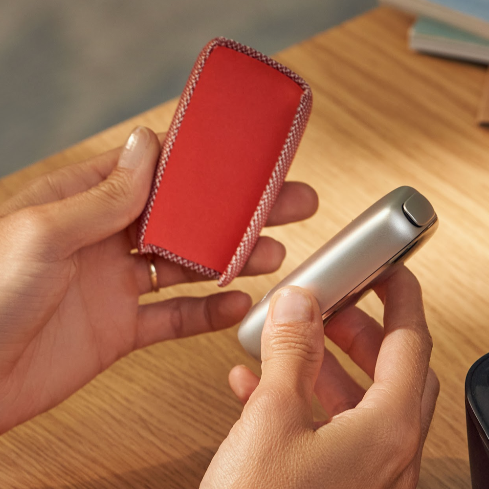 Ploom X Advanced textilný zadný kryt red spolu so zariadením v rukách