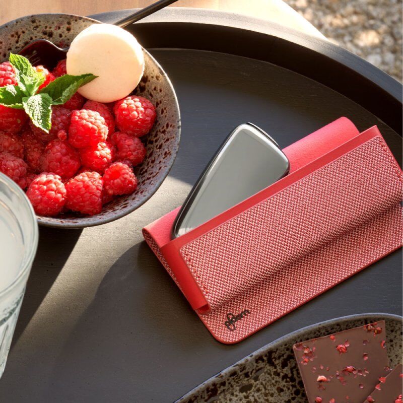 Čerené textilné puzdro s Ploom X Slate Grey zariadením na stole